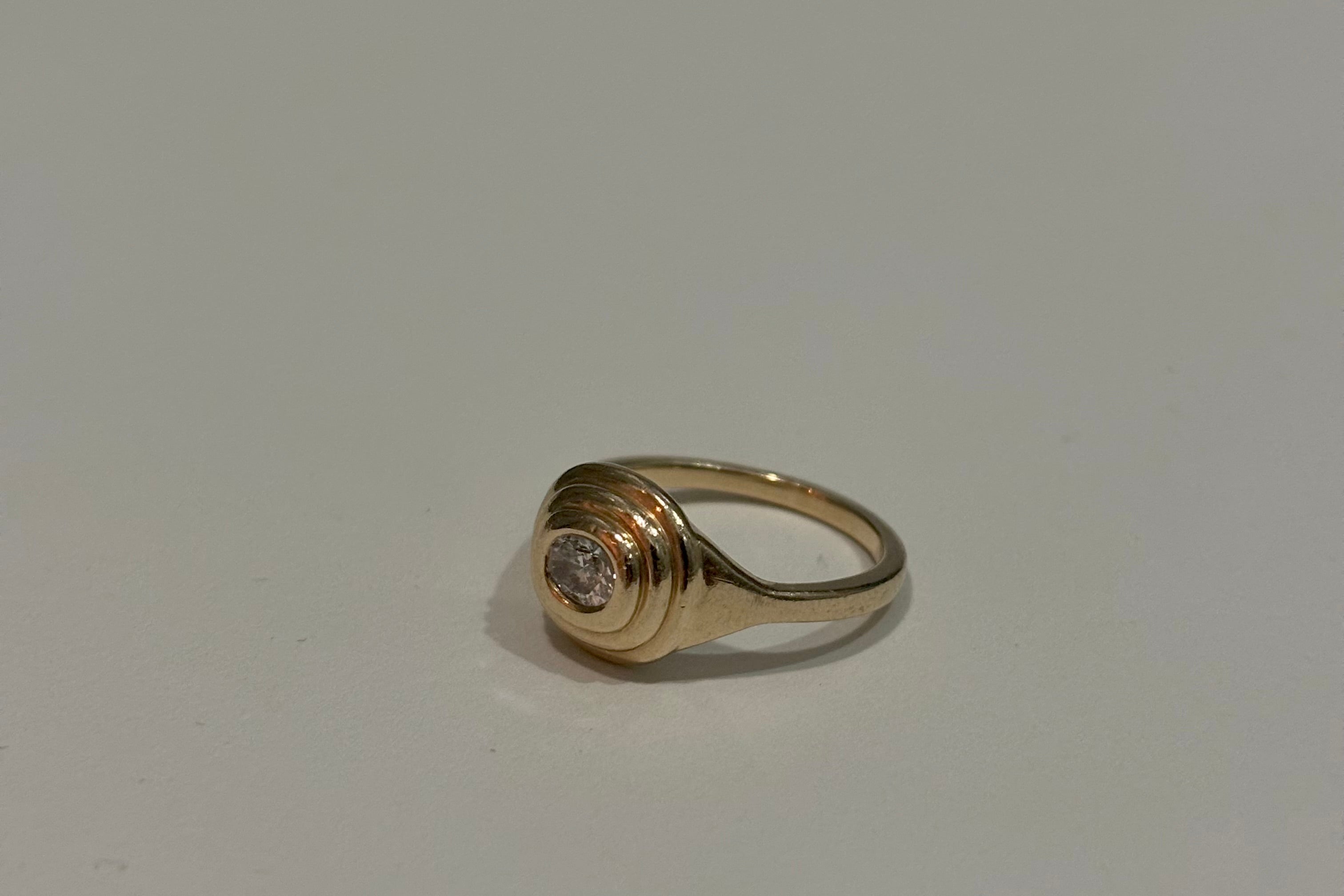 Gold ring with a diamond on a light gray background